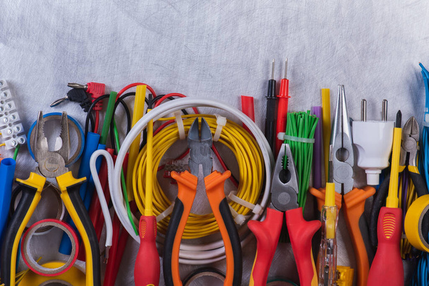 Diferentes herramientas de mano, componentes y accesorios para usar en instalaciones eléctricas en vista superior de fondo metálico - Foto, Imagen