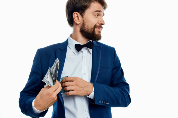 un uomo ricco in un abito classico su uno sfondo leggero con un fascio di soldi in mano - Foto, immagini