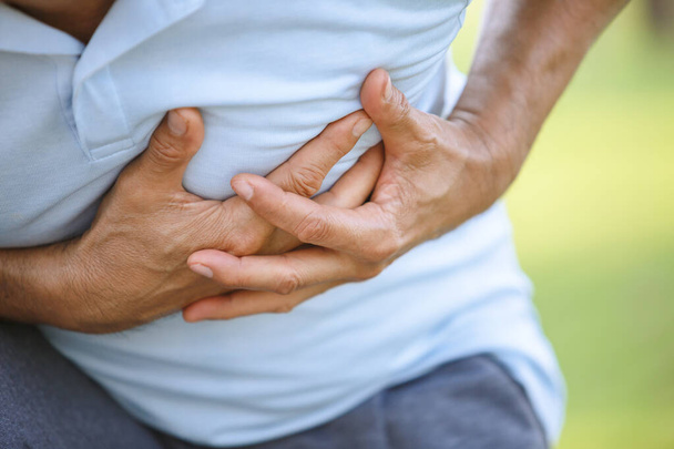 Close-up hand aanraken borst met pijnlijke, mannen lijden pijn op de borst. hartinfarct en gezondheidszorg. - Foto, afbeelding