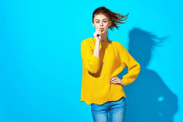 attractive woman in yellow sweater and jeans casual wear emotions posing blue background - Фото, изображение