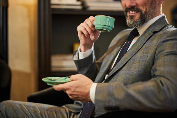 Respectabele man in een pak genietend van een kopje thee - Foto, afbeelding