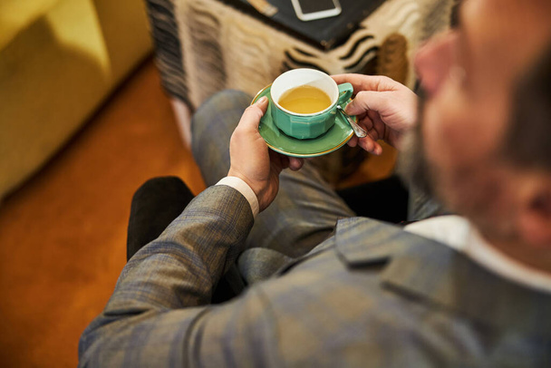 Fragmentfoto eines Mannes im Anzug, der Tee trinkt - Foto, Bild