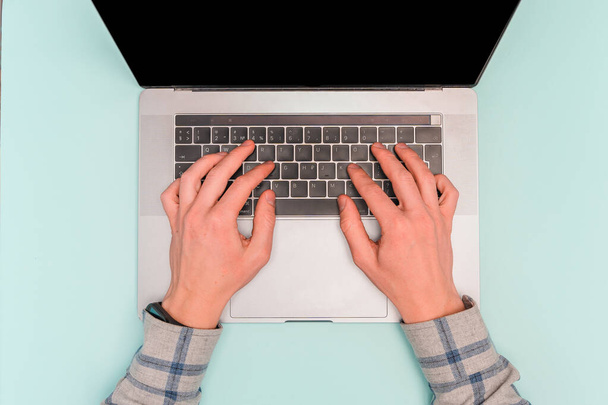 Men's hands work behind laptops on a blue desk, top view and space for text - Photo, Image