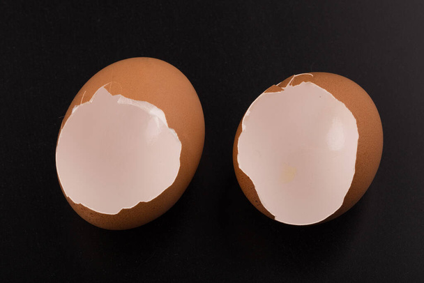 Розбите яйце в яєчній шкаралупі наполовину ізольоване на чорному тлі
 - Фото, зображення