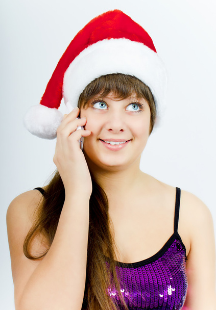 Happy smiling girl with Santa hat with a phone - Foto, afbeelding