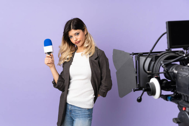 Reportera adolescente sosteniendo un micrófono y reportando noticias aisladas sobre fondo púrpura con expresión triste y deprimida - Foto, Imagen