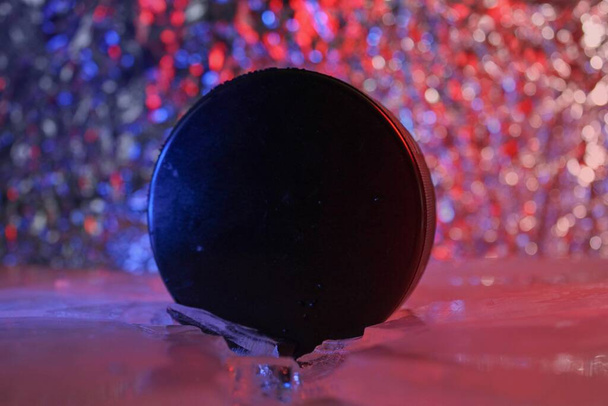 Disco da hockey si trova sul bordo in ghiaccio rotto. Gli cade addosso una luce rosso-blu. Concetto di hockey ceco. Il disco da hockey ha rotto il ghiaccio. Lunga vita al Campionato del Mondo di Hockey. - Foto, immagini