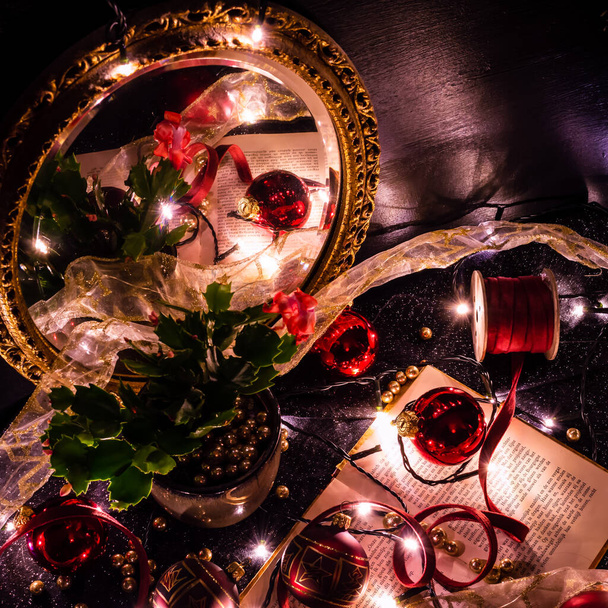 Noël nature morte d'un livre, boules de Noël, boules d'or, rubans et une plante réfléchissant dans un miroir d'or - Photo, image