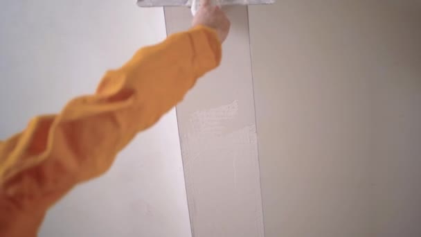 un réparateur expérimenté plâtre le plafond avec une truelle, et avec un mortier moderne blanc, effectue le plâtre. vue du bas - Séquence, vidéo