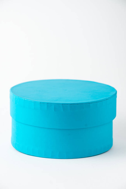Κοντινό πλάνο του στρογγυλού μπλε κουτιού, σε λευκό φόντο, κάθετα, με χώρο αντιγραφής - Φωτογραφία, εικόνα