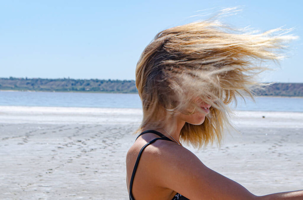 Větrné počasí, bílý pohled na poušť. Blonďaté vlasy ženy se třepetaly větrem. Kvalitní fotografie - Fotografie, Obrázek