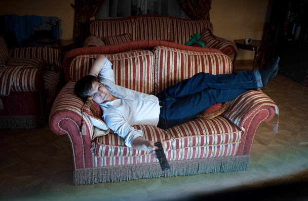 hombre cambiando los canales de televisión en el sofá por la noche
 - Foto, Imagen