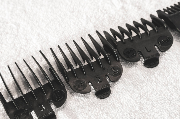 Różne czarne spinacz do włosów Comb Przewodnik załączniki do elektrycznego strzyżenia włosów na białym ręczniku w fryzjera. - Zdjęcie, obraz