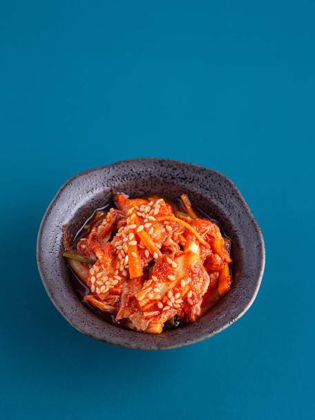 Plats traditionnels coréens ou Kimchi dans un bol sur fond bleu. Espace pour le texte. Concept des aliments coréens. - Photo, image