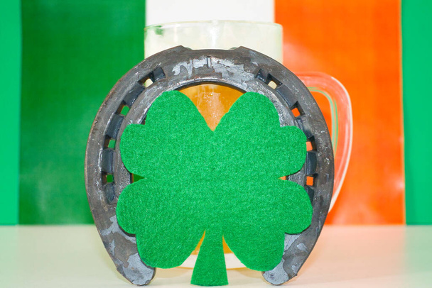 lucky horseshoe op bier mok met groene achtergrond en Ierse vlag - Foto, afbeelding