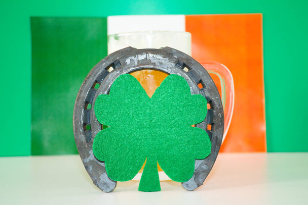 chanceux fer à cheval sur tasse de bière avec fond vert et drapeau irlandais - Photo, image