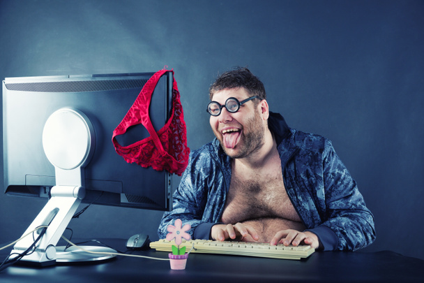 Mann sitzt am Schreibtisch und schaut auf Computerbildschirm - Foto, Bild
