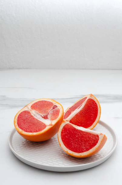 Вертикальне зображення. Соковитий і смачний грейпфрут на сірій тарілці, кухонний стіл. Порожній простір
 - Фото, зображення