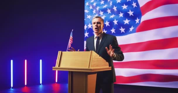 Candidato presidencial dando discurso contra bandera de EE.UU. - Metraje, vídeo