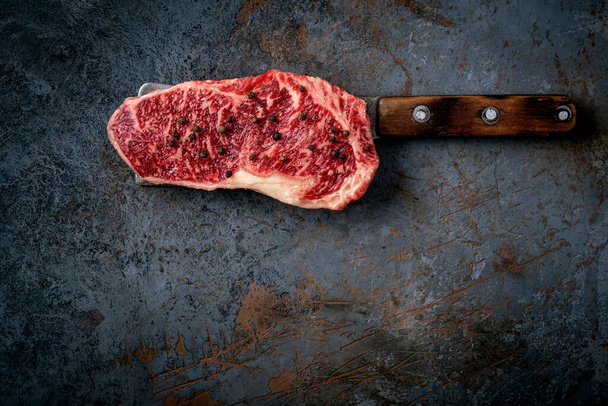Syrový hovězí steak na sekáčku na tmavém kamenném stole, pohled shora a kopírování prostoru - Fotografie, Obrázek