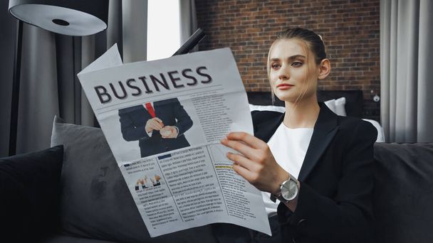 бизнесвумен в формальной одежде читает деловую газету в номере отеля - Фото, изображение