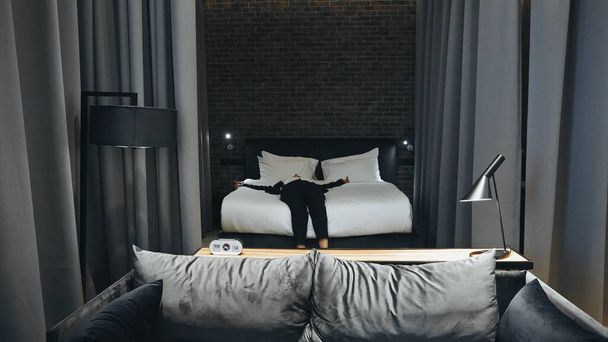 деловая женщина в формальной одежде лежит на кровати в номере отеля - Фото, изображение