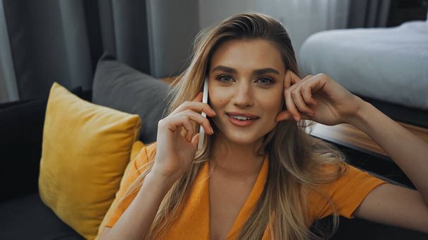 happy young woman talking on smartphone in hotel room  - Valokuva, kuva