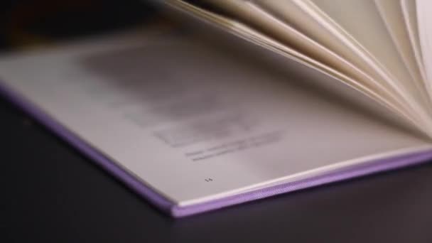 Macro shot of closing violet book. Closeup of turning pages of book. love of reading concept. Detailed view of unrecognizable text on sheets - Footage, Video