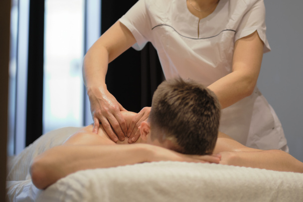 Gros plan de l'homme profitant d'un massage relaxant des épaules. Homme relaxant sur table de massage recevant massage - Photo, image