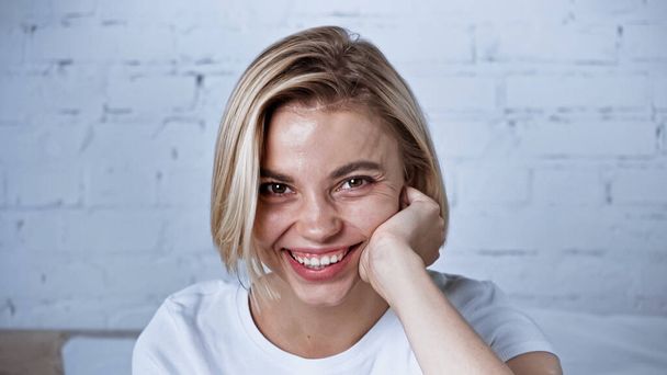 cheerful young woman smiling at camera in bedroom - Fotografie, Obrázek