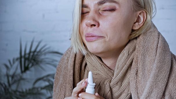 ill woman frowning with closed eyes while using nasal spray - Photo, Image