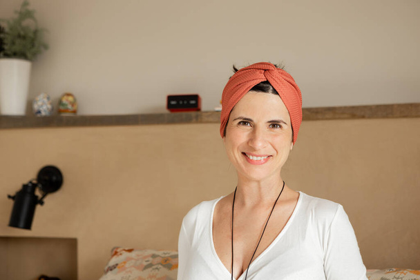 Portrait of caucasian smiling woman with home clothes, turban, hippie indian style, looking at camera. Happy Healthy vegan young mother on her 30s, in peace, confident, self-convinced. close-up. - Photo, image