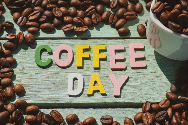 Gebrande koffiebonen met koffie dag formulering op de houten achtergrond. - Foto, afbeelding