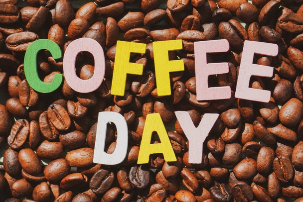 Gebrande koffiebonen met koffie dag formulering op de houten achtergrond. - Foto, afbeelding