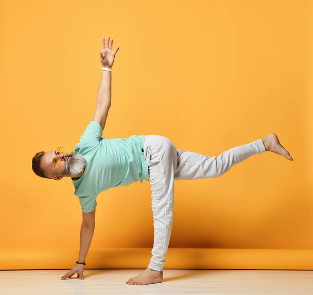 Mature man practicing yoga in Ardha Chandrasana asana pose - Фото, изображение