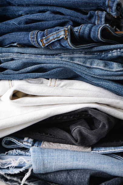 Gevouwen jeans op grijze achtergrond. Een close-up. Verticaal. - Foto, afbeelding