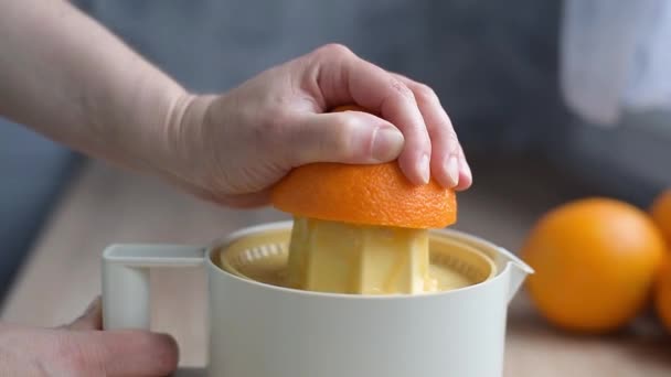 Το θηλυκό χέρι συμπιέζει χυμό από βιολογικά πορτοκάλια σε αποχυμωτή - Πλάνα, βίντεο