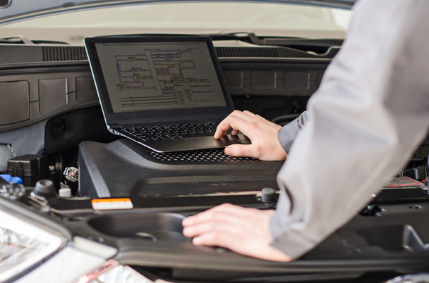 Mecânico com laptop diagnostica carro na oficina
. - Foto, Imagem