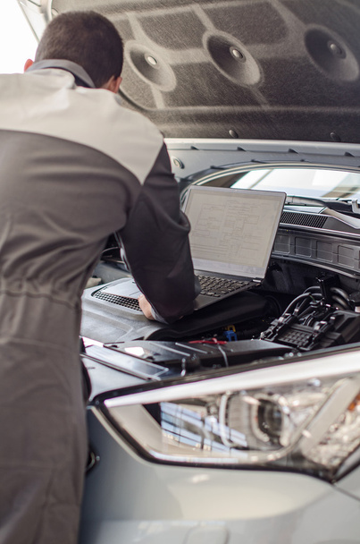 Mechanic met laptop diagnose auto in werkplaats. - Foto, afbeelding