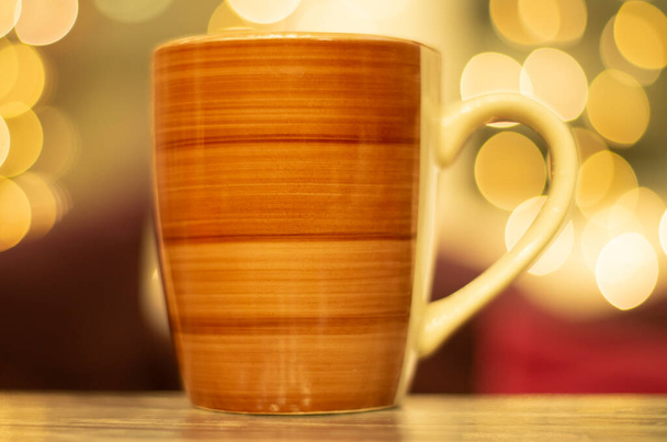 Tasse à café sur table en bois avec des lumières de Noël floues en arrière-plan. - Photo, image