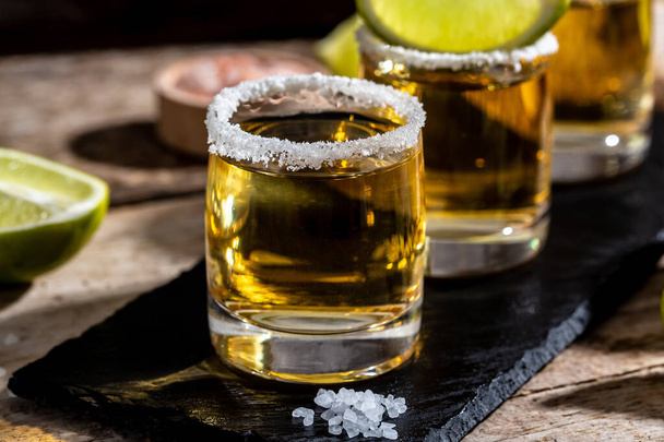 Tequila mexicano con lima y sal sobre fondo negro rústico. espacio para el texto. bebida de lujo. Concepto de bebida alcohólica. - Foto, imagen