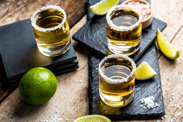 Tiros de tequila con sal y lima Bebida nacional mexicana. Tomas de tequila dorados. Bebida nacional mexicana. vista superior. - Foto, imagen