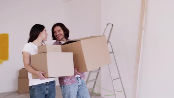 Junges glückliches Paar von Hauskäufern, die Kisten tragen, in ihre neue Wohnung kommen, Zeitlupe - Filmmaterial, Video