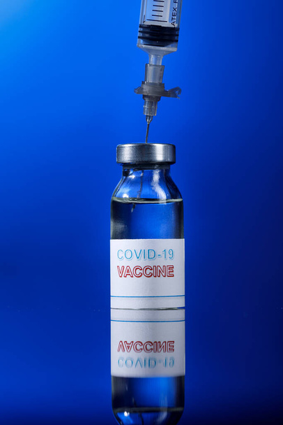 Kék hátterű vakcinával ellátott fecskendő - Fotó, kép