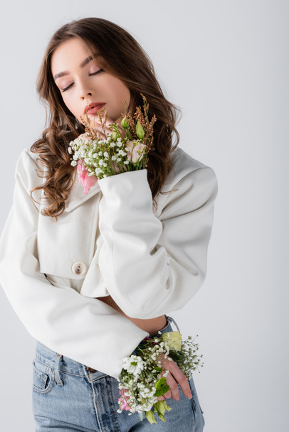 Woman with different flowers in sleeves of jacket posing isolated on grey  - Foto, immagini