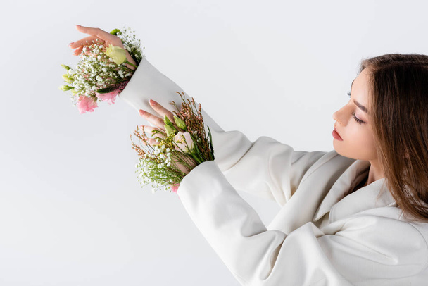 Woman looking at flowers in sleeves of blazer isolated on grey  - Fotoğraf, Görsel