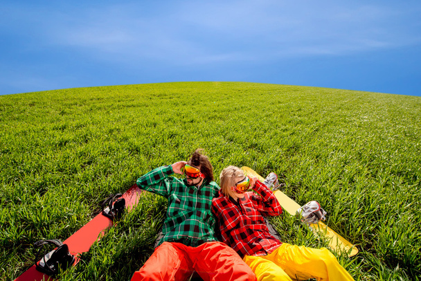 Couple in sportswear with snowboards lying on the grass - Photo, Image