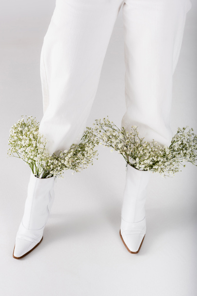 Cropped view of baby breath flowers in shoes of woman on grey background - Photo, image