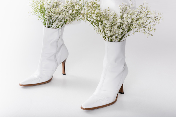 Cropped view of legs of woman in white shoes with small flowers on grey background - Photo, Image