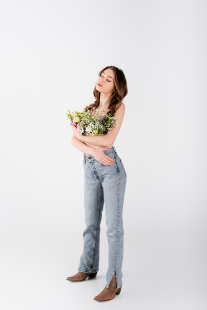 Brunette model with flowers in blouse standing with closed eyes on grey background - Photo, Image